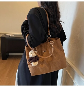 Detail of brown woven tote bag with metal ring hardware and cute bear keychain