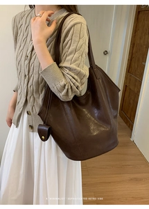 Mannequin portant un grand sac fourre-tout en cuir marron foncé au style rétro français