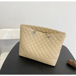 Close-up of beige quilted tote bag featuring silver chain strap and matte leather finish