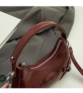 Detail of burgundy leather handbag showing thick handles and elegant metallic zipper