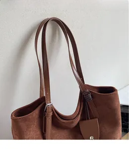 Détail de la bandoulière réglable en cuir et de la texture en daim marron de ce sac cabas
