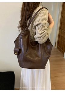 Sac fourre-tout rétro marron porté à l'épaule d'un mannequin en pull en maille