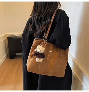 Detailed close-up of brown woven texture tote bag with cute teddy bear charm pendant