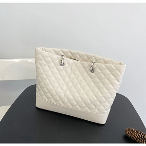 Detail of quilted off-white tote bag featuring a silver metal chain and leather strap