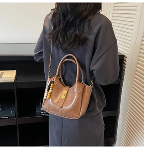 Bolso tipo cubo vintage marrón de cuero sintético con cierre dorado y cuentas en un modelo