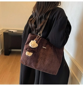 Detailed macro view of dark brown quilted tote bag material with plush bear charm