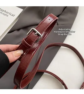 Close-up of adjustable wine red crocodile embossed strap with silver buckle hardware