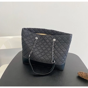 Detailed macro view of black quilted tote bag featuring chain straps and durable leather base