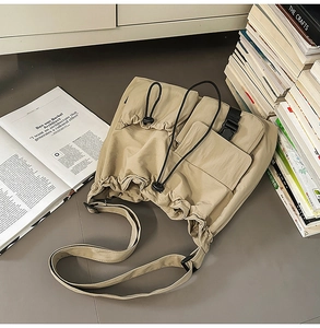Detail view of khaki drawstring bucket bag with buckle strap on a minimalist setup