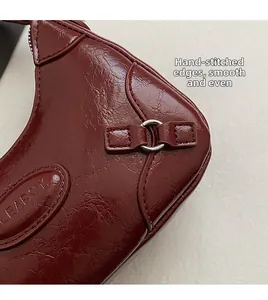 Detail showing handcrafted stitching and glossy wrinkled burgundy leather texture