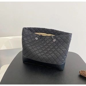Close-up of the diamond quilted texture and sleek leather base on this black tote bag