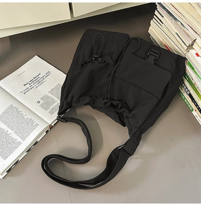 Top view of a black techwear drawstring bucket bag with multiple functional pockets