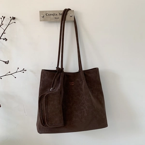 Detail of dark brown tote bag with suede texture and hanging small zipper pouch accessory
