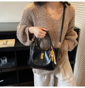 Detalle del bolso de cuero negro con cierre metálico dorado y colgante de cuentas de colores