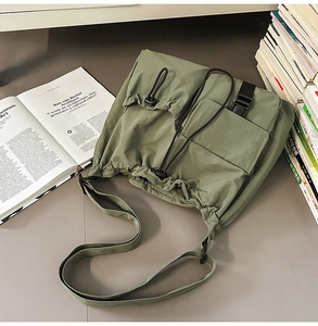Detail view of dark green nylon bucket bag featuring drawstring closure and buckle pocket