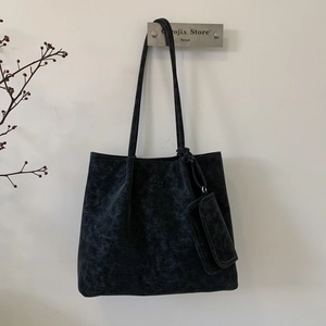 Close-up of black textured leather tote bag with PAN TOR logo and small pouch charm