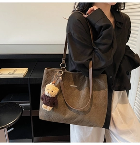 Detailed macro view of dark brown tote bag featuring textured diamond patterns and bear charm