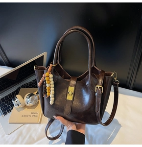 Detalle de bolso vintage marrón con cierre giratorio dorado y colgante de cuentas