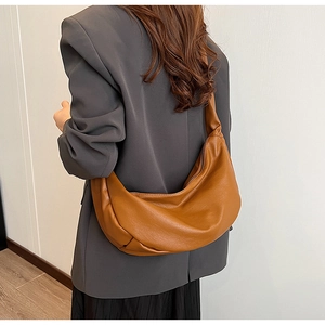 Detail einer großen braunen Leder-Hobo-Tasche, getragen von einem Modell im urbanen Stil