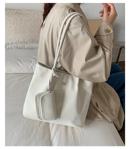 Detail view of cream white tote bag featuring soft PU leather texture and a matching mini pouch