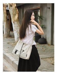 Detail of off-white canvas drawstring bucket bag with multiple pockets and black buckle