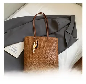 Close-up of brown woven tote bag texture with colorful bead tassel on grey blazer