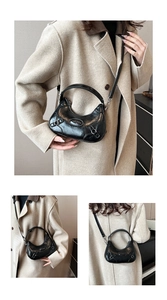 Detail of black glossy crescent bag with silver buckle and removable leather strap
