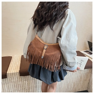Détail du sac à bandoulière en daim marron avec de longues franges et une boucle en métal