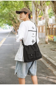 Detail of black drawstring bucket bag with buckle pocket and adjustable shoulder strap