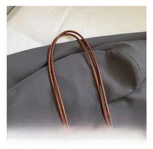 Detail show of woven leather texture and sturdy handle on the brown tote bag