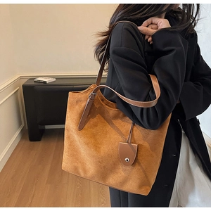 Vue latérale d'un sac cabas en daim caramel avec lanières en cuir et étiquette décorative