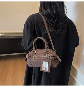 Detail view of brown Boston bag with shoulder strap and cute cartoon bear tag