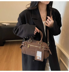 Close-up of brown Boston handbag with gold hardware and cartoon card holder detail