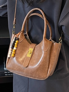 Bolso bucket retro de cuero marrón con colgante de cuentas y cierre de giro en color dorado