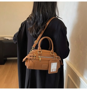 Brown leather Boston bag shown on model in a minimalist urban interior setting