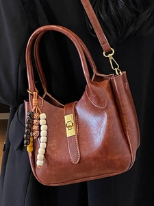Bolso cubo vintage de cuero marrón con cuentas de madera sobre fondo de abrigo negro