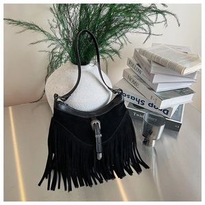 Gros plan sur un sac à franges noir avec boucle western sur table métallique