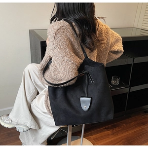 Détail d'un grand sac cabas vintage noir en daim porté à l'épaule pour femme