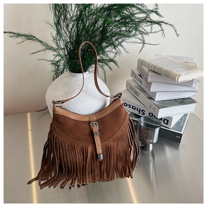 Détail du sac à bandoulière en daim marron avec franges bohèmes et boucle métallique