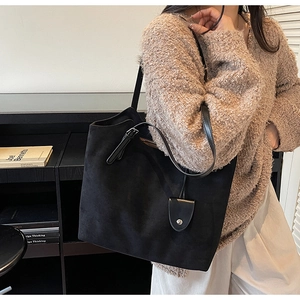 Gros plan sur le sac cabas noir mat montrant la texture en daim et la boucle argentée