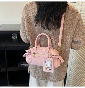 Detailed view of a pink Boston bag with buckle accents and a detachable card holder tag