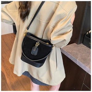 Detailansicht der schwarzen Eimertasche aus Leder mit goldenen Beschlägen an einem Model
