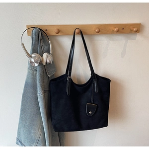 Détail d'un grand cabas noir sur crochet en bois avec denim et casque audio chic