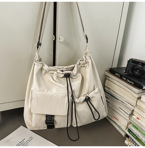 Detail of beige nylon bucket bag with adjustable strap and multiple utility pockets