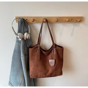 Détail du sac cabas vintage en daim marron avec sangle en cuir sur crochet en bois