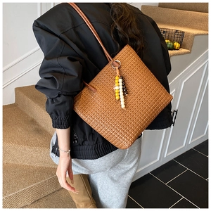 Close-up of brown woven tote bag featuring detailed texture and colorful beaded tassel charm
