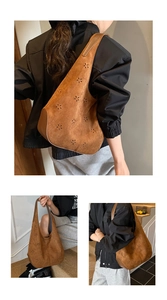 Detail view of brown suede bucket bag with intricate floral hollow-out carving and wide strap