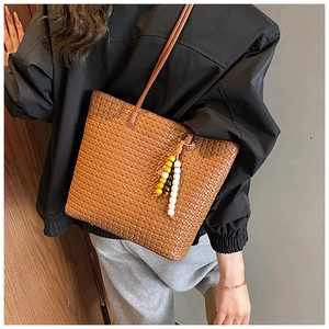 Close-up of vintage brown woven tote bag with colorful wooden bead tassel charm