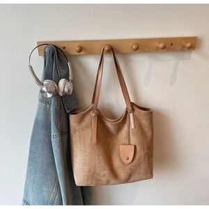 Détail d'un sac cabas en daim marron chaud avec doubles anses sur un crochet en bois