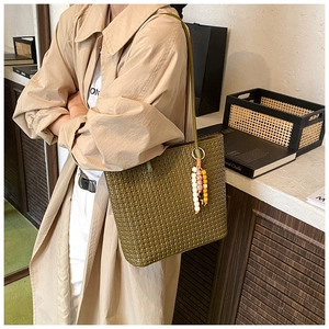 Olive green woven tote bag with colorful wooden beads shown in an aesthetic setting